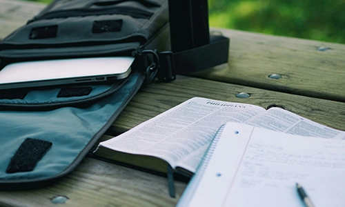 Laptop in a bag and notesbooks on a picnic table